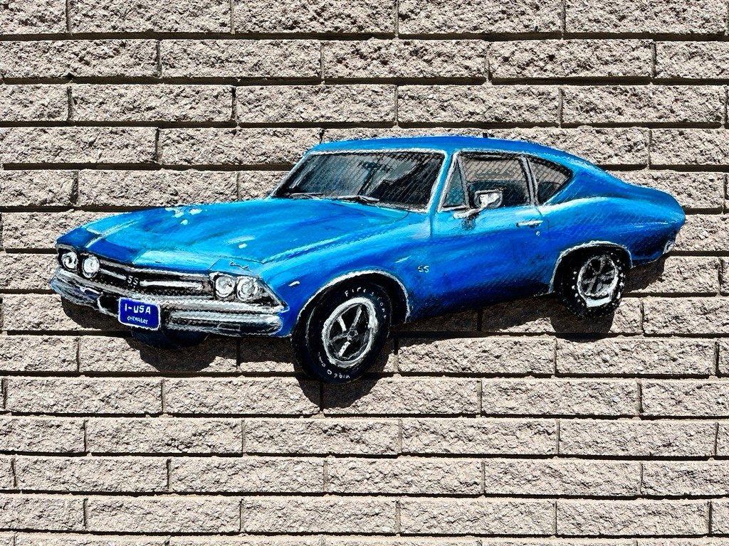 Custom hand-cut and hand-painted blue Chevelle SS cutout on a brick wall