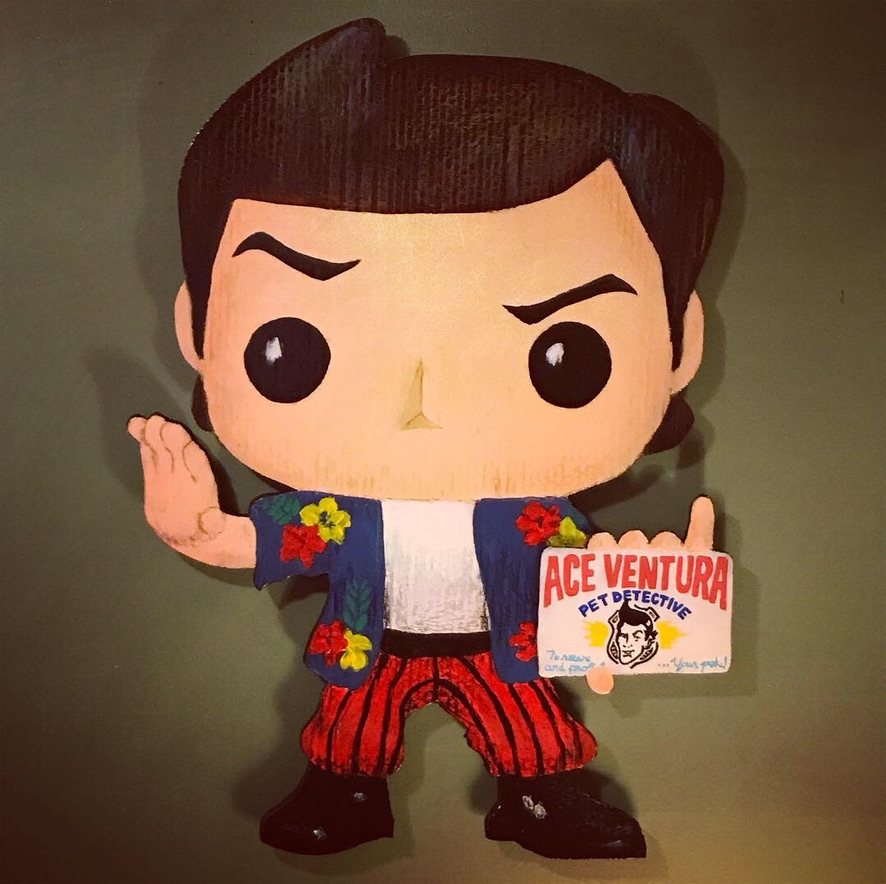 Hand-cut and hand-painted Funko Pop style Ace Ventura, Pet Detective, in a flowered shirt and red striped pants holding his business card, on a green wall