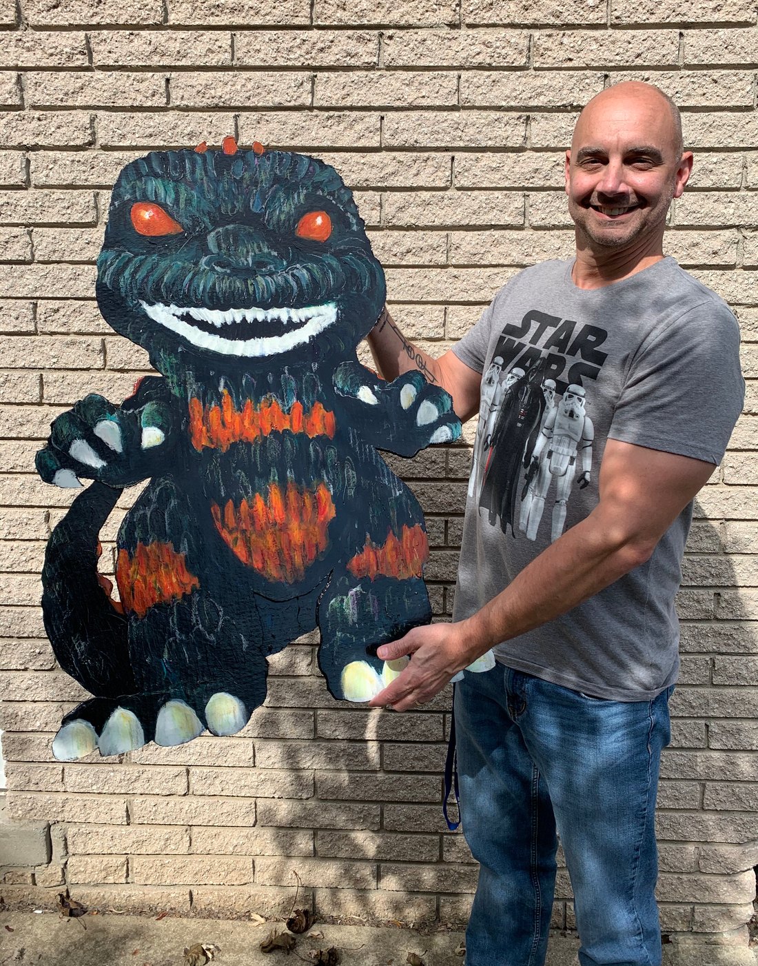 Jeremy's client holding the hand-painted Godzilla Funko Pop cutout