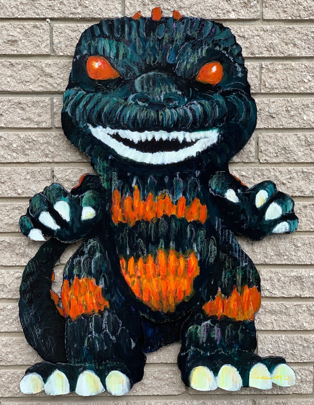 Hand-painted Godzilla Funko Pop cutout on a brick wall