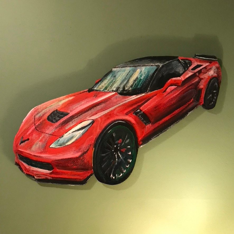 Custom hand-cut and hand-painted red Corvette Z06 cutout on a green wall